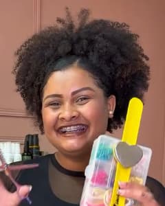Mikaellen, de cabelo crespo preso no alto da cabeça.